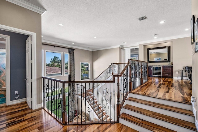 stairway with wood-type flooring, a textured ceiling, and crown molding