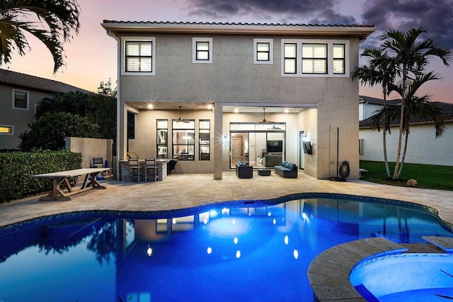 pool at dusk featuring a patio area, an outdoor bar, and an outdoor hangout area