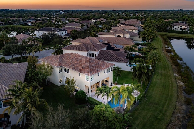 aerial view at dusk featuring a water view