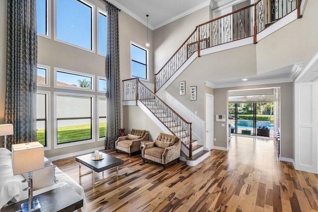 living room featuring a high ceiling, plenty of natural light, ornamental molding, and wood-type flooring