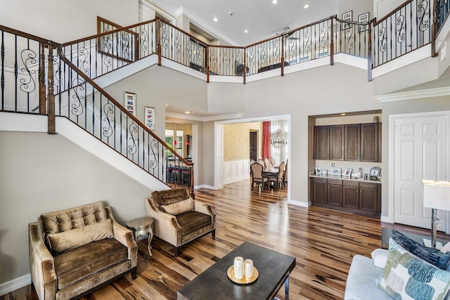 living room featuring a high ceiling, ornamental molding, and wood-type flooring