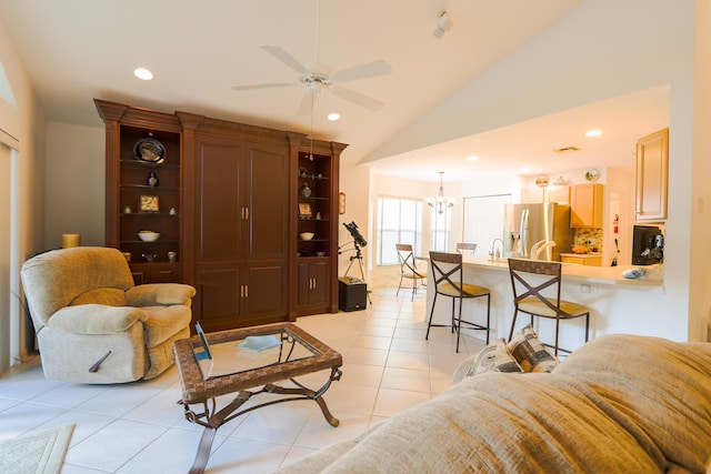 living room with light tile patterned flooring, ceiling fan with notable chandelier, and high vaulted ceiling