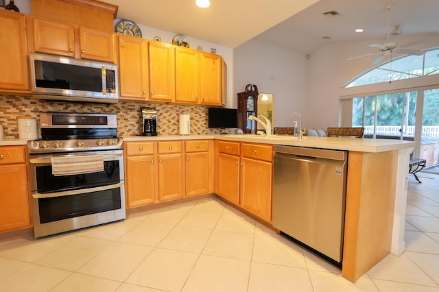 kitchen with kitchen peninsula, backsplash, stainless steel appliances, and lofted ceiling