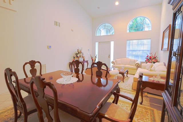 dining space with high vaulted ceiling and light tile patterned floors