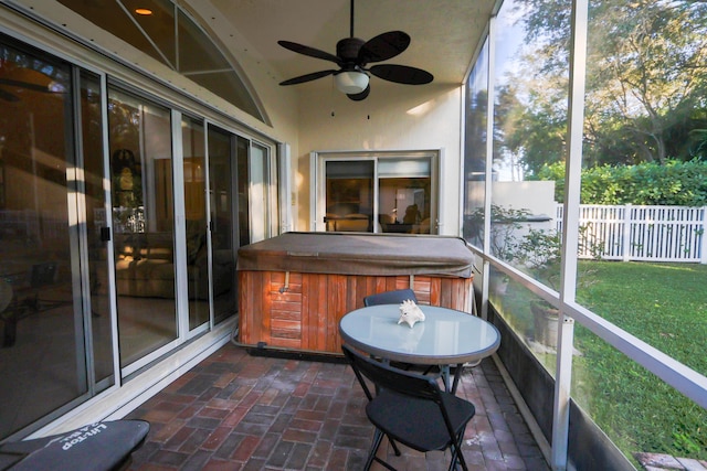 unfurnished sunroom featuring ceiling fan and a hot tub