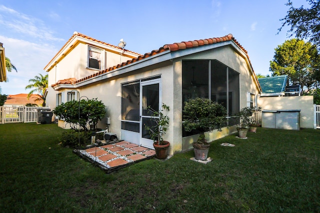 back of house featuring a sunroom and a lawn