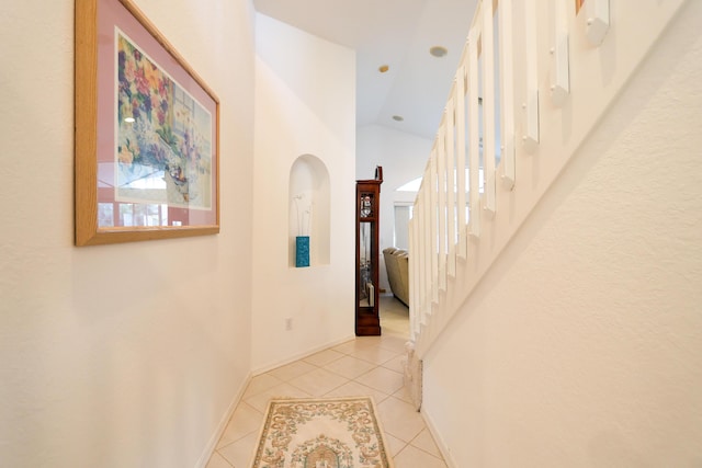 corridor featuring light tile patterned floors and high vaulted ceiling