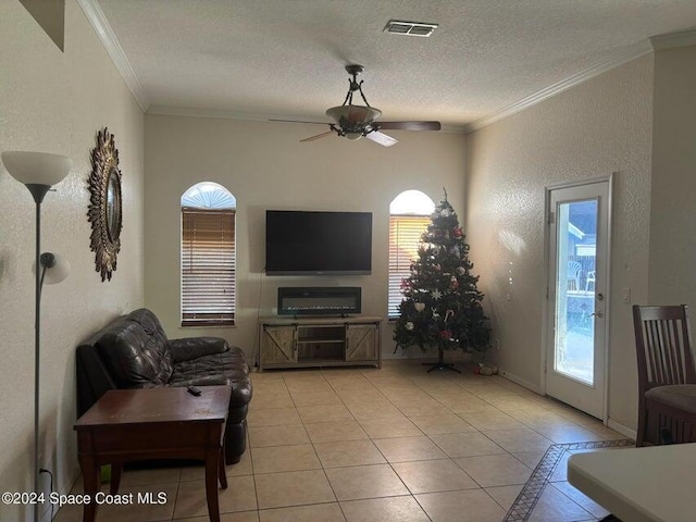 tiled living room featuring ceiling fan, plenty of natural light, a textured ceiling, and ornamental molding