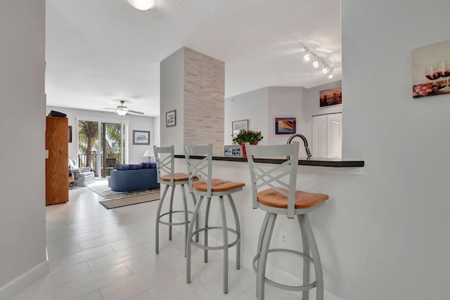 kitchen with kitchen peninsula, a kitchen breakfast bar, ceiling fan, and sink