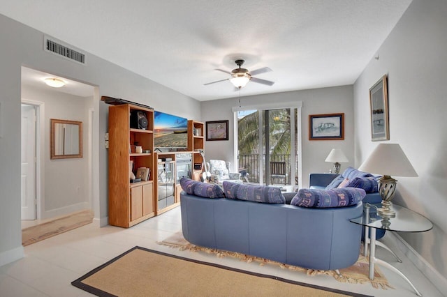 living room featuring ceiling fan, light tile patterned flooring, and a textured ceiling