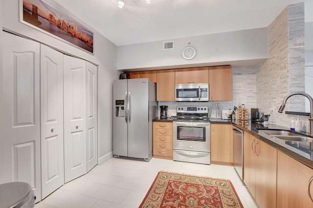 kitchen with backsplash, sink, light tile patterned floors, and stainless steel appliances