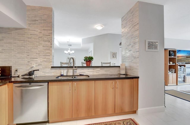 kitchen featuring sink, decorative light fixtures, an inviting chandelier, dark stone countertops, and dishwasher