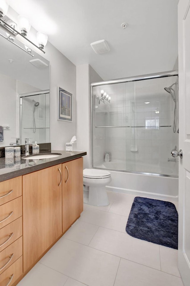 full bathroom with tile patterned flooring, vanity, toilet, and bath / shower combo with glass door