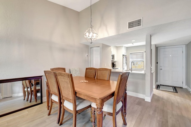 dining area featuring sink, light hardwood / wood-style floors, and a notable chandelier