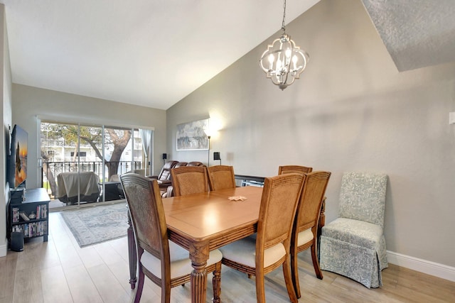 dining room featuring light hardwood / wood-style floors, an inviting chandelier, and vaulted ceiling