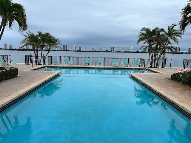 view of pool with a water view and a patio