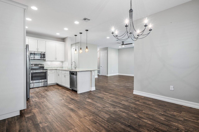 kitchen featuring dark wood-type flooring, white cabinets, sink, hanging light fixtures, and appliances with stainless steel finishes