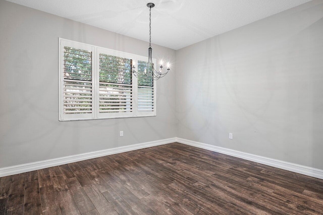 unfurnished dining area featuring dark wood-type flooring and an inviting chandelier