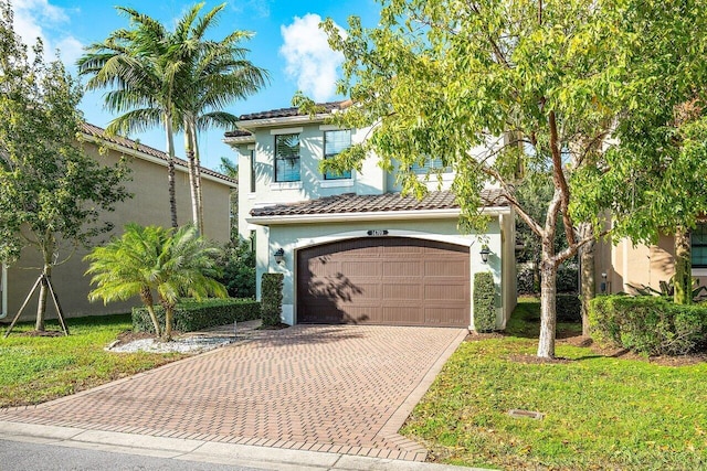 mediterranean / spanish home featuring a garage and a front lawn