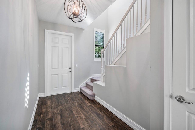 entryway featuring a textured ceiling, dark hardwood / wood-style floors, and a notable chandelier