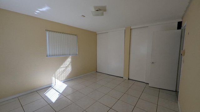 unfurnished bedroom with light tile patterned floors and two closets