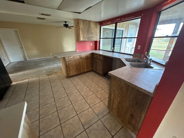 kitchen featuring kitchen peninsula, light tile patterned floors, ceiling fan, and sink