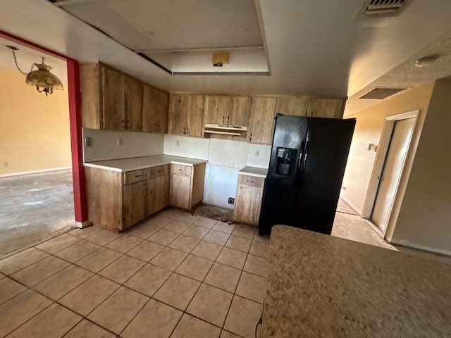 kitchen with black fridge with ice dispenser and light tile patterned floors