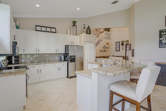 kitchen featuring white cabinets, stainless steel appliances, an island with sink, sink, and ornamental molding