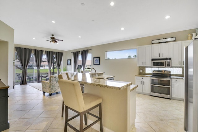 kitchen with a breakfast bar area, appliances with stainless steel finishes, white cabinetry, and sink