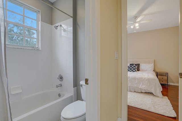 bathroom featuring toilet, ceiling fan, tiled shower / bath, and wood-type flooring