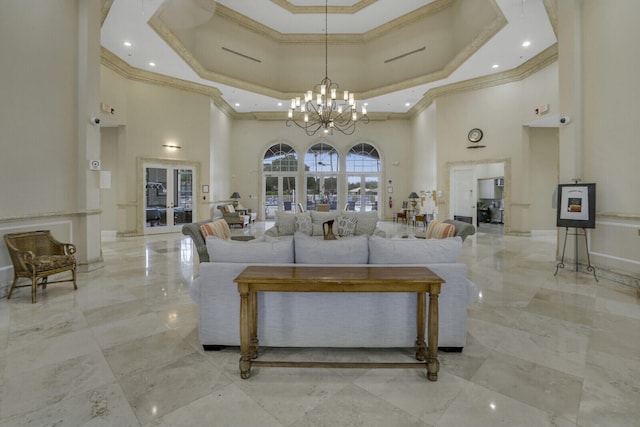 living room featuring a chandelier, a tray ceiling, crown molding, and a towering ceiling