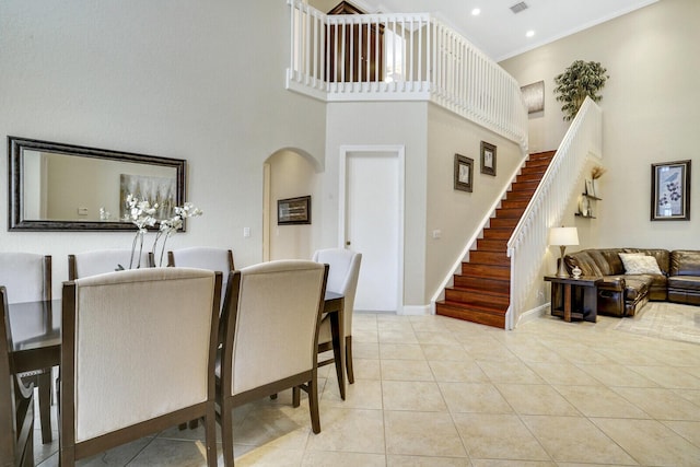 tiled dining room featuring ornamental molding and a high ceiling