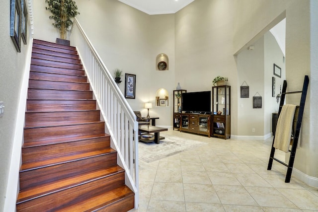 stairway with a towering ceiling and tile patterned floors