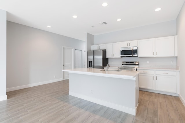 kitchen with white cabinets, a center island with sink, sink, and appliances with stainless steel finishes