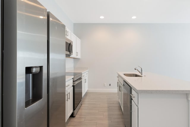 kitchen with white cabinets, sink, appliances with stainless steel finishes, and an island with sink