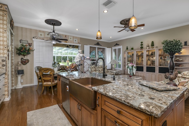 kitchen with dishwasher, sink, hanging light fixtures, dark hardwood / wood-style floors, and a center island with sink