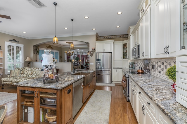 kitchen with decorative backsplash, light stone countertops, decorative light fixtures, white cabinetry, and stainless steel appliances