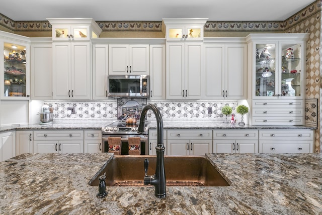 kitchen featuring backsplash, stone counters, white cabinetry, and sink