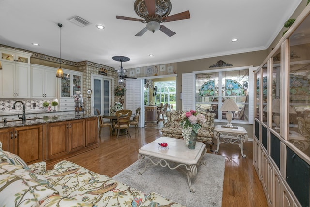 living room with ceiling fan, crown molding, sink, and light hardwood / wood-style flooring