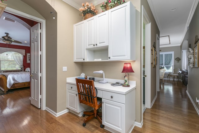 office with hardwood / wood-style flooring, ceiling fan, built in desk, and ornamental molding