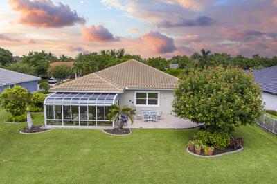 back house at dusk featuring a sunroom, a patio area, and a yard