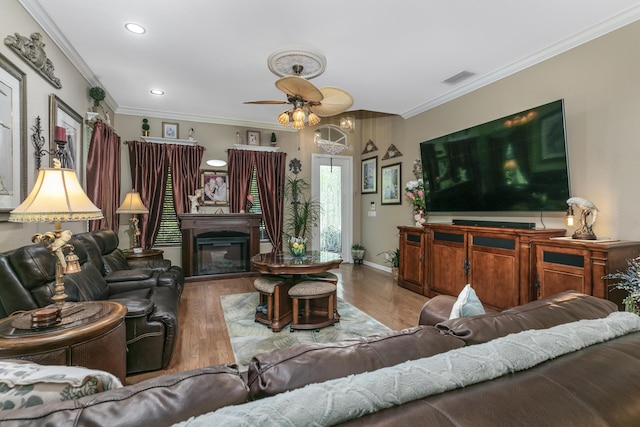 living room featuring hardwood / wood-style flooring, ceiling fan, and ornamental molding