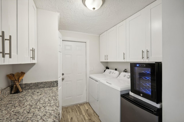 washroom featuring cabinets, a textured ceiling, crown molding, washing machine and dryer, and light hardwood / wood-style floors