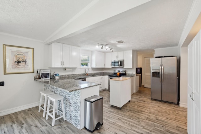 kitchen with a textured ceiling, white cabinetry, kitchen peninsula, and stainless steel appliances