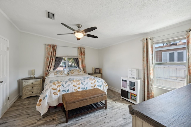 bedroom with ceiling fan, wood-type flooring, a textured ceiling, and ornamental molding