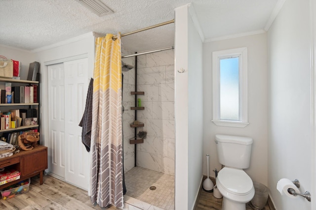 bathroom with walk in shower, wood-type flooring, a textured ceiling, toilet, and ornamental molding