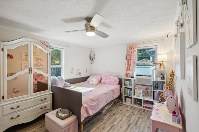 bedroom with ceiling fan, light hardwood / wood-style floors, and a textured ceiling