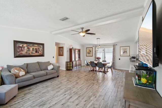 living room with ceiling fan, lofted ceiling with beams, light wood-type flooring, and a textured ceiling