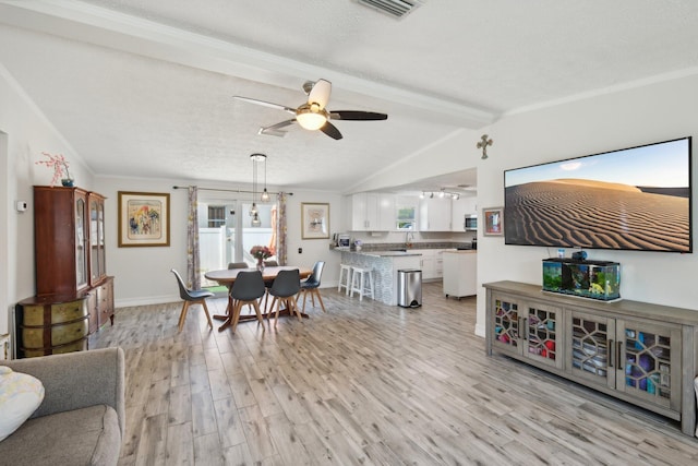 living room with vaulted ceiling with beams, crown molding, light hardwood / wood-style floors, and a textured ceiling