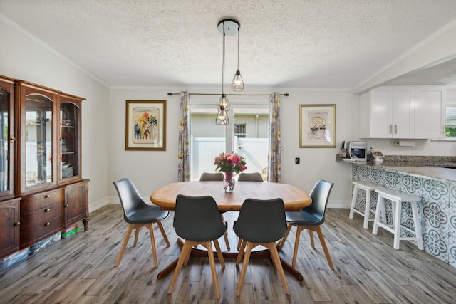 dining space featuring a textured ceiling, light wood-type flooring, and ornamental molding